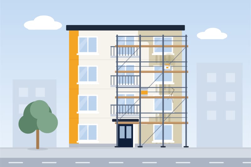 İskele kurulmuş üç katlı apartmanda dış cephe boyası: cephenin bir bölümü yeni boyanmış